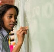 A teacher writing on a chalkboard