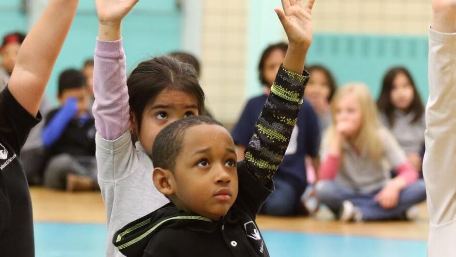 Young students raising their hands.
