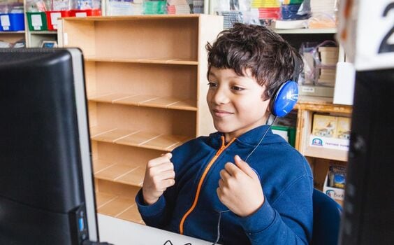 A student with headphones interacting with a computer.