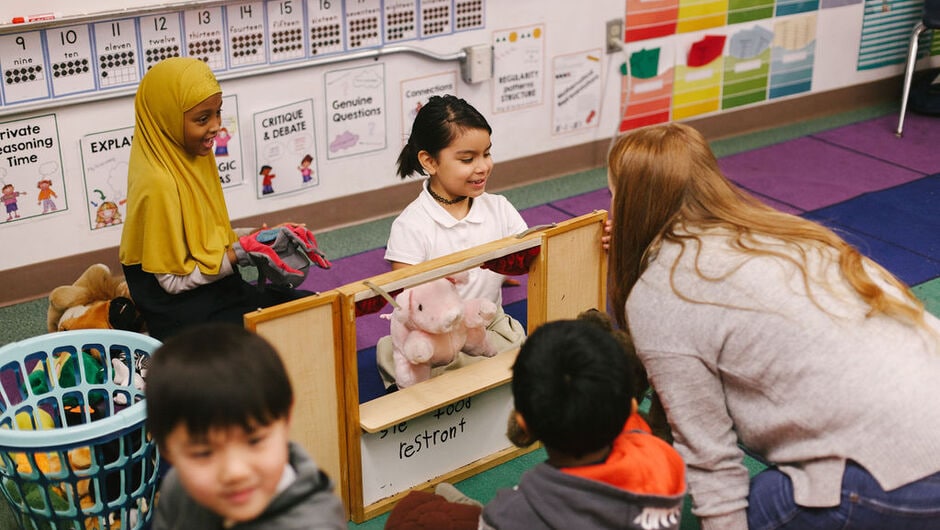 Alt text: Students play games on the carpet of a classroom