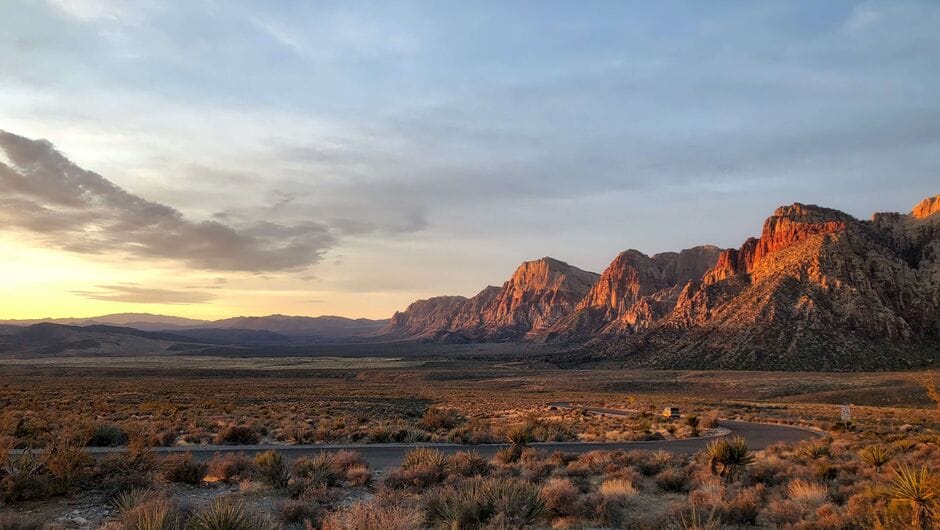 A scene of a desert with red mountains in the distance.