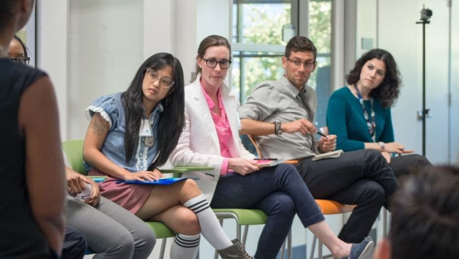 Teachers sit in a line during a teacher training exercise