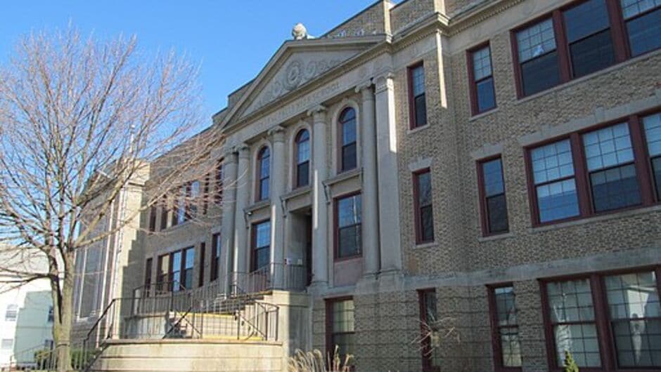 A stone high school building reads Central Falls High School engraved over the door.