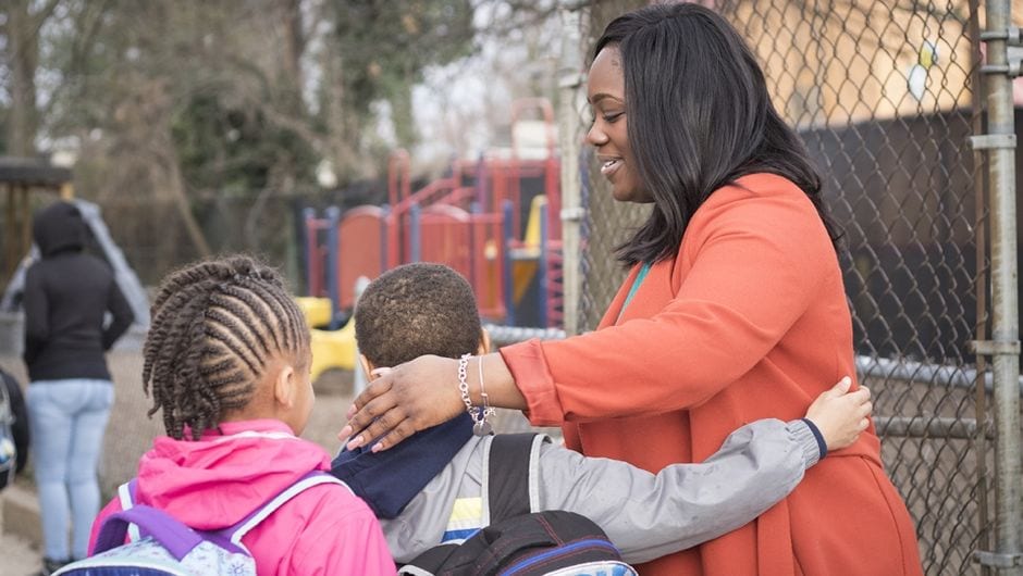A teacher sees students off outside of the playground after school
