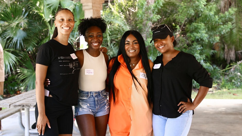 Four people stand shoulder to shoulder outdoors