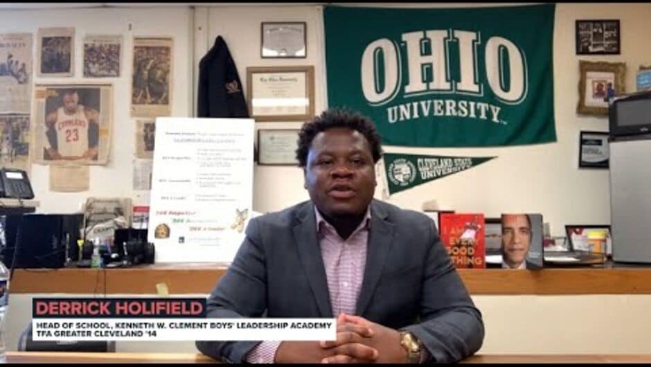 A man sits at a desk in front of a shelf of books and an Ohio flag.