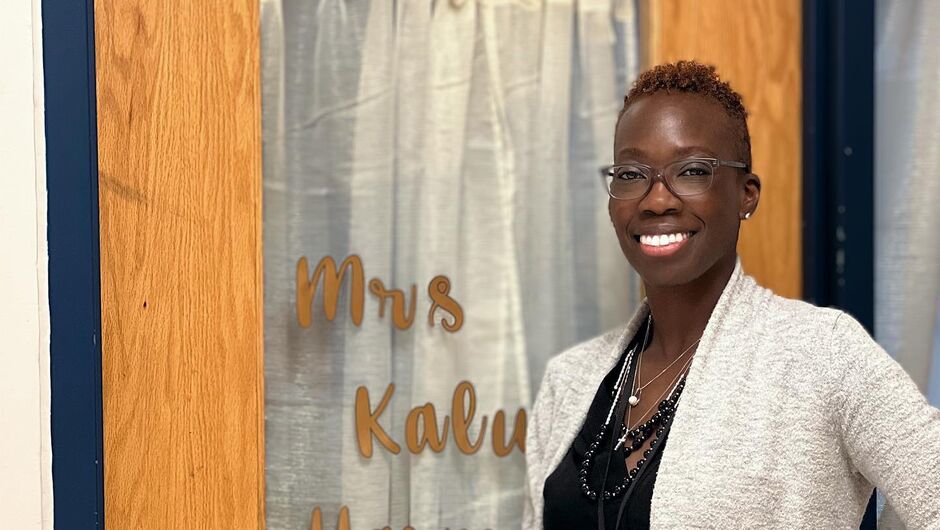 A person stands in front of a glass classroom door. 