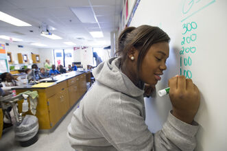 Alt text: a student writes on a white board