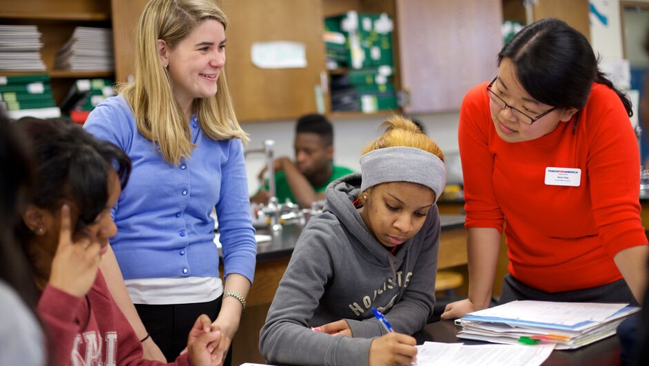 Alt text: two teachers help students in a classroom