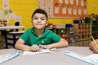 A student sits at his desk completing a workbook