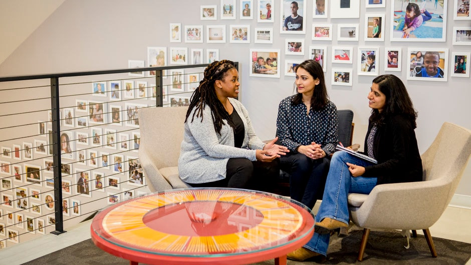 Three people sitting together in an office talking.