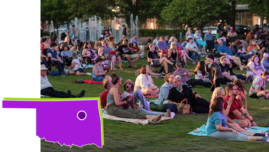 Image of perople on the lawn enjoying a performace with their community
